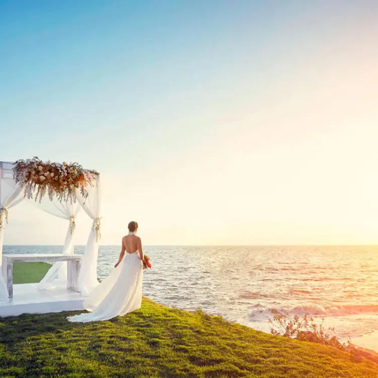 Bride standing by a beachfront wedding gazebo at sunset at Marriott Puerto Vallarta, Puerto Vallarta