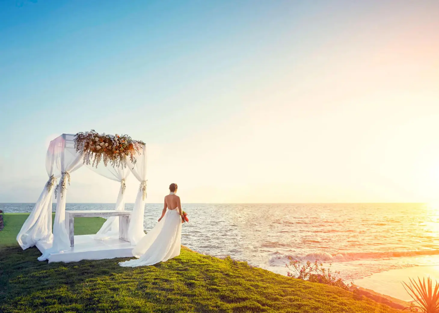 Bride standing by a beachfront wedding gazebo at sunset at Marriott Puerto Vallarta, Puerto Vallarta