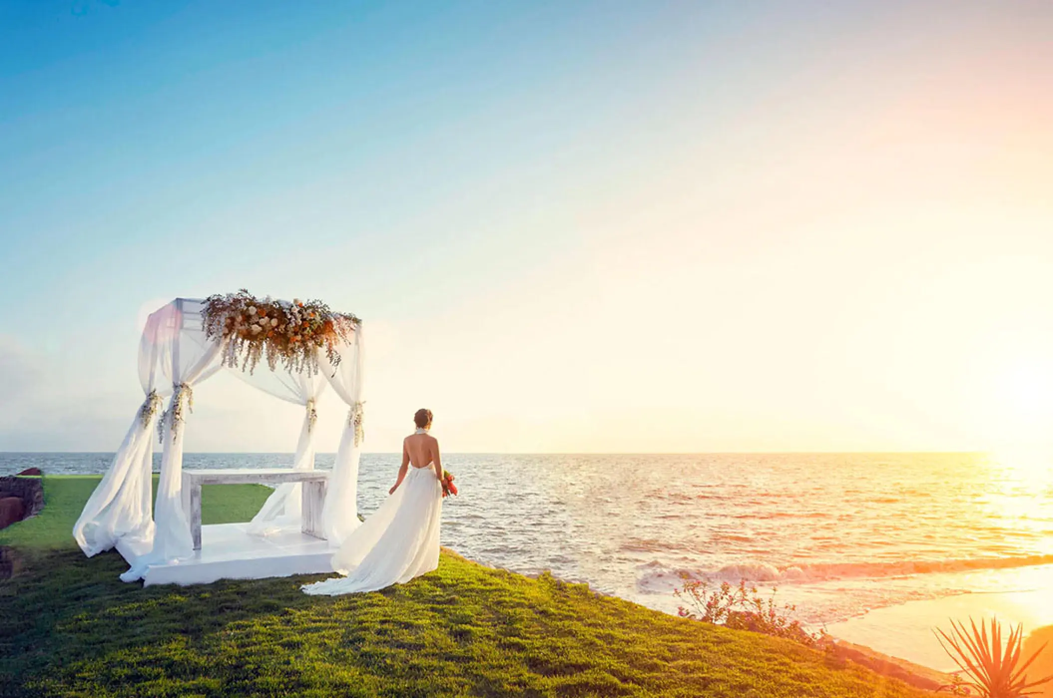 Bride standing by a beachfront wedding gazebo at sunset at Marriott Puerto Vallarta, Puerto Vallarta