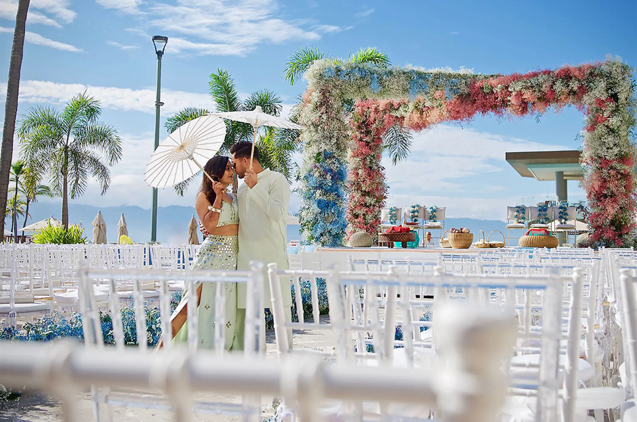 Couple with white parasols by a floral arch at Marriott Puerto Vallarta, Puerto Vallarta