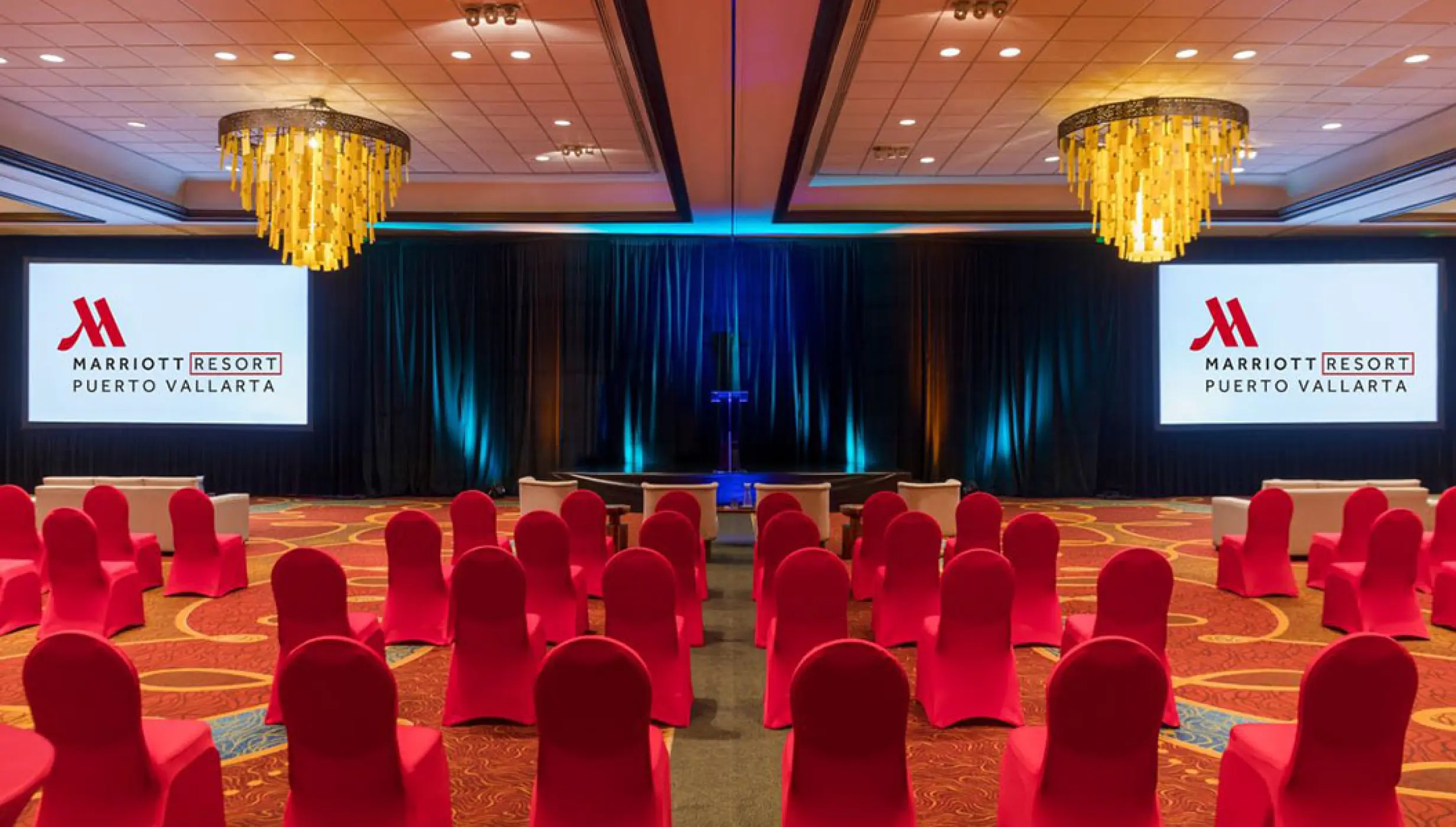 Indoor ballroom wedding reception at Marriott Puerto Vallarta with red chairs and gold chandeliers, Puerto Vallarta