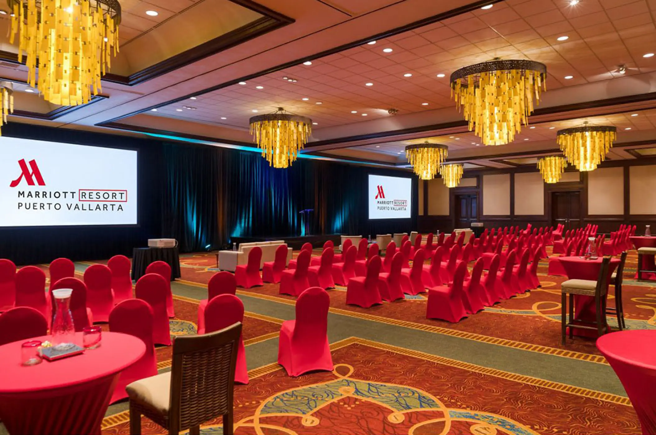 Indoor ballroom with red seating and gold chandeliers for a wedding reception at Marriott Puerto Vallarta