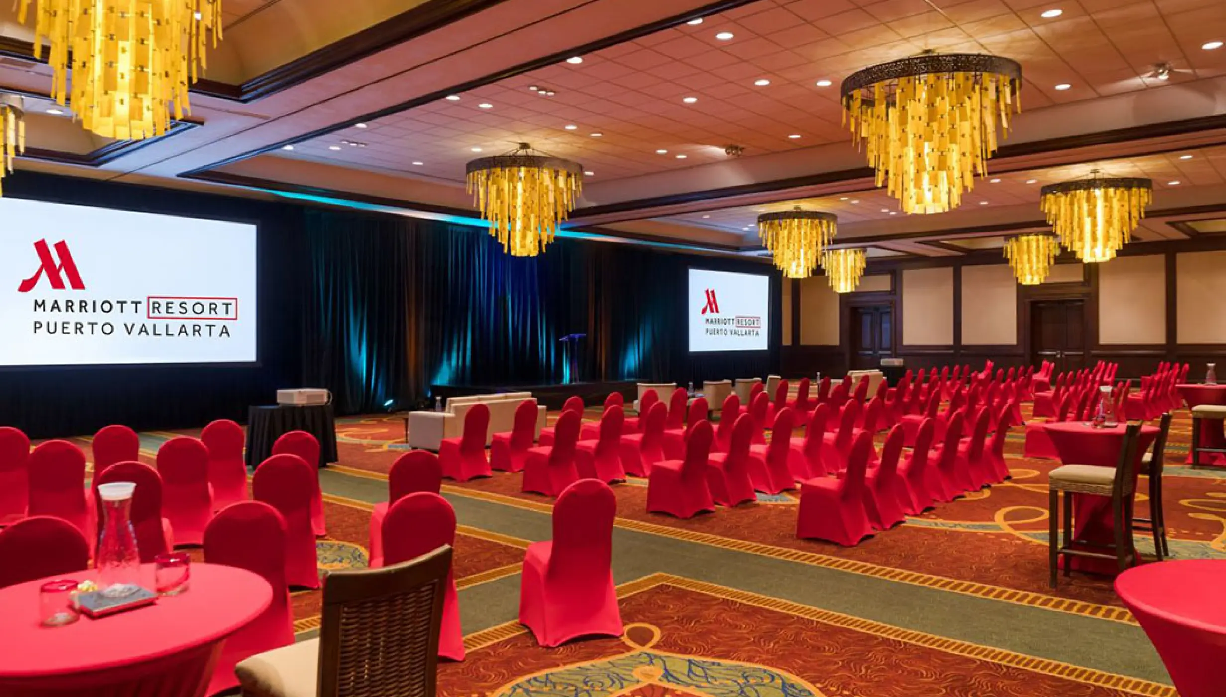 Indoor ballroom with red seating and gold chandeliers for a wedding reception at Marriott Puerto Vallarta