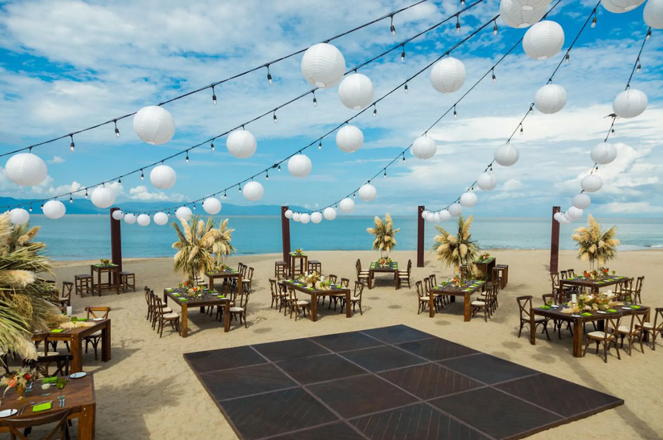 Beach wedding reception setup with paper lanterns and dance floor at Marriott Puerto Vallarta, Puerto Vallarta