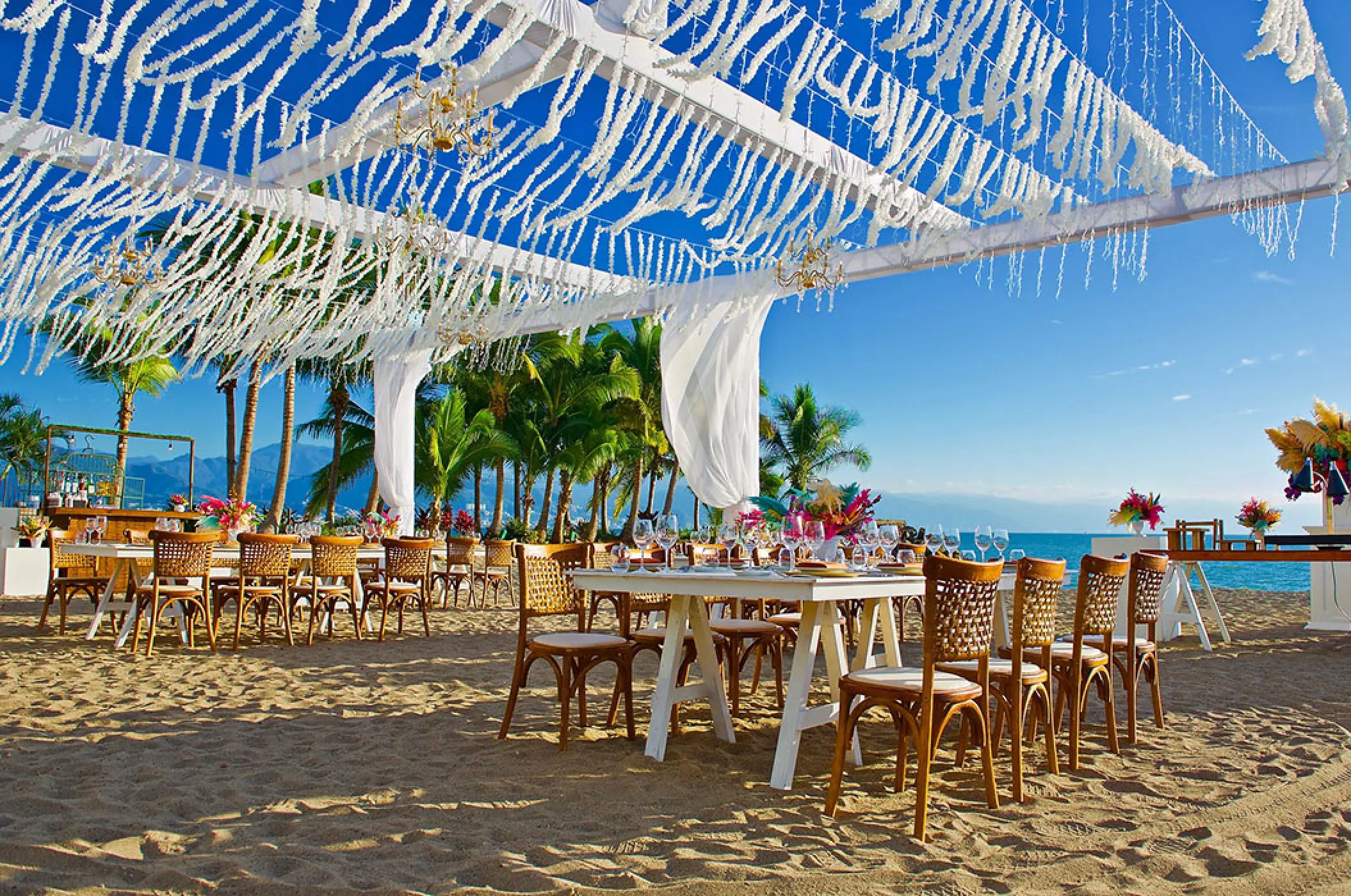 Beach wedding reception with white canopy and wooden chairs at Marriott Puerto Vallarta, Puerto Vallarta