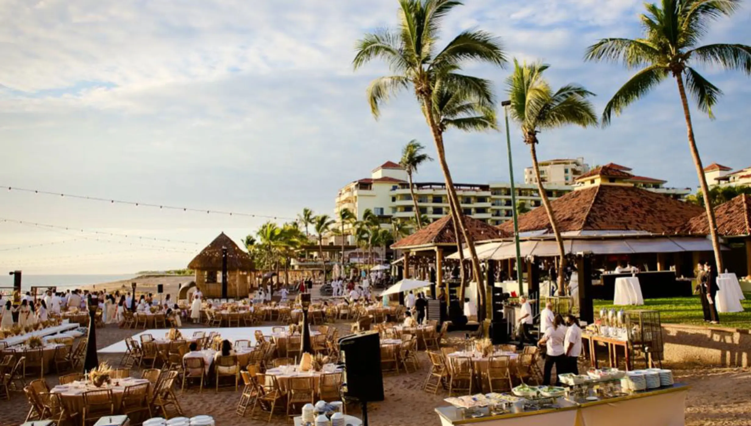 Beachfront wedding reception setup with round tables and palm trees at Marriott Puerto Vallarta