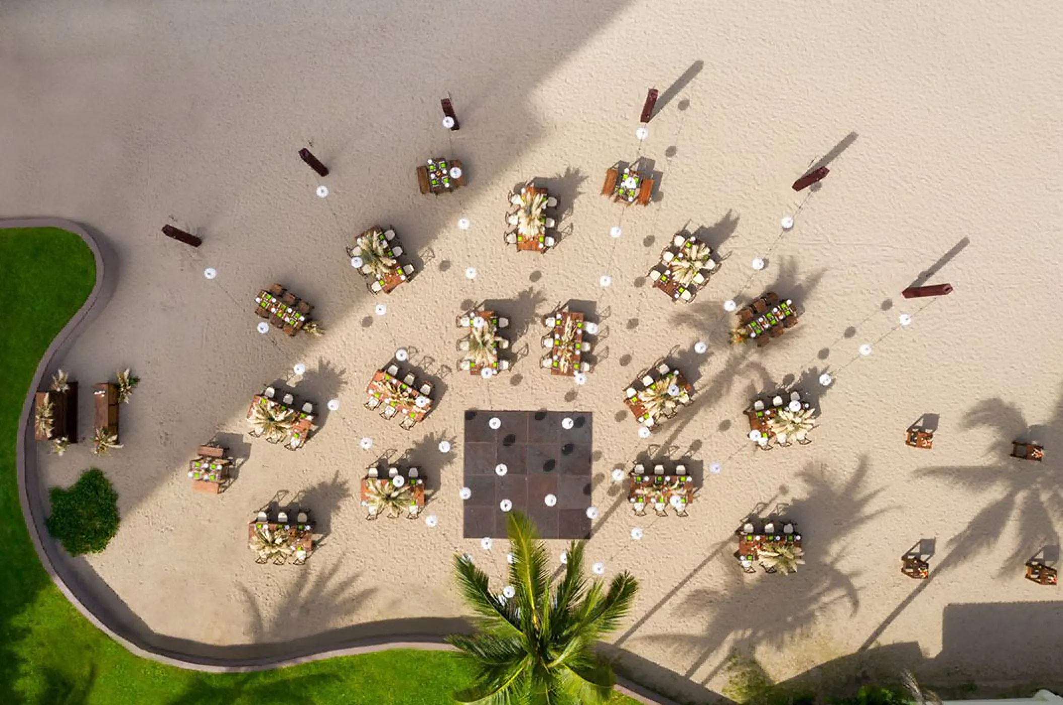 Aerial view of a beach wedding reception with round tables and a dance floor at Marriott Puerto Vallarta