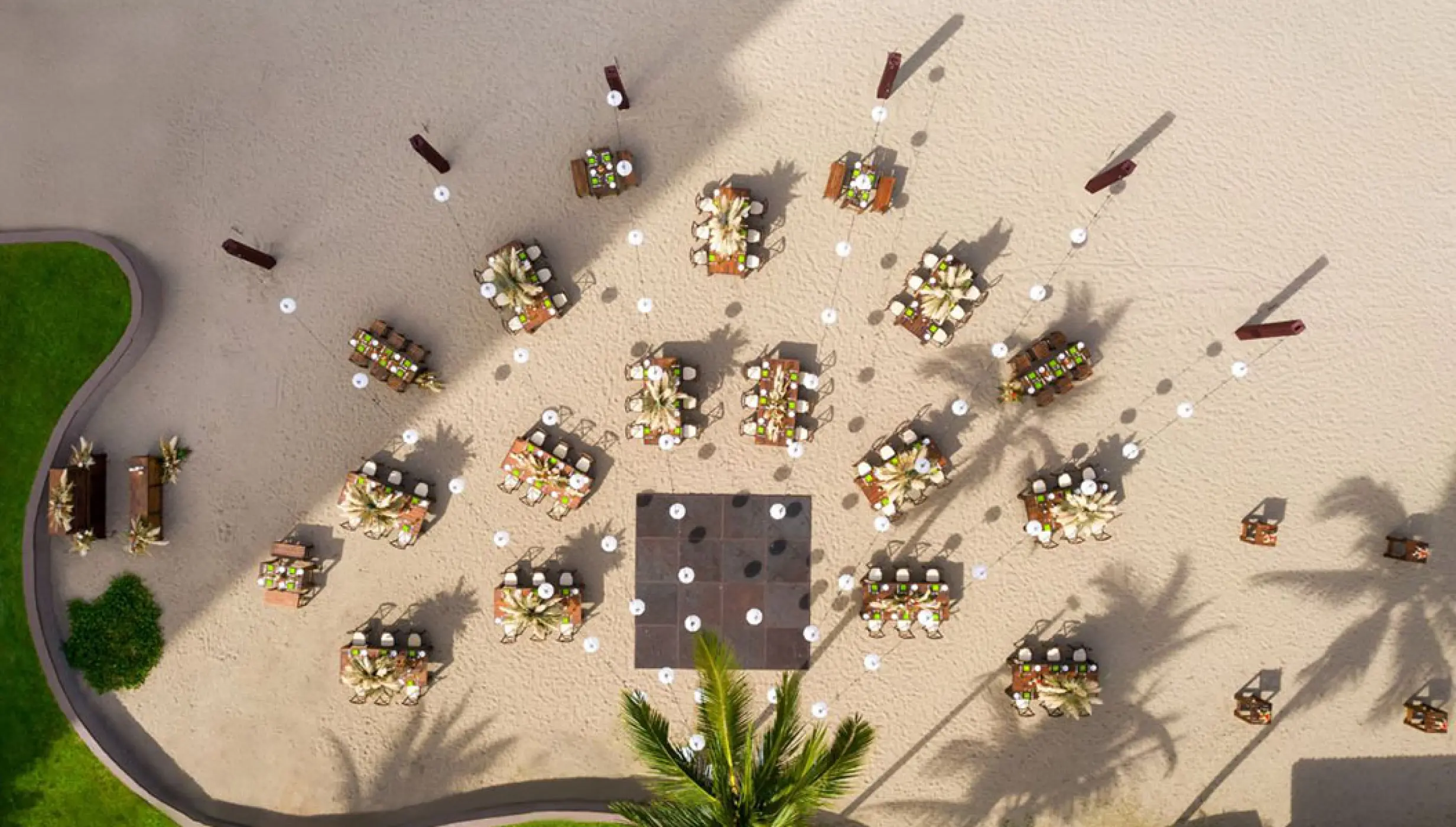 Aerial view of a beach wedding reception with round tables and a dance floor at Marriott Puerto Vallarta