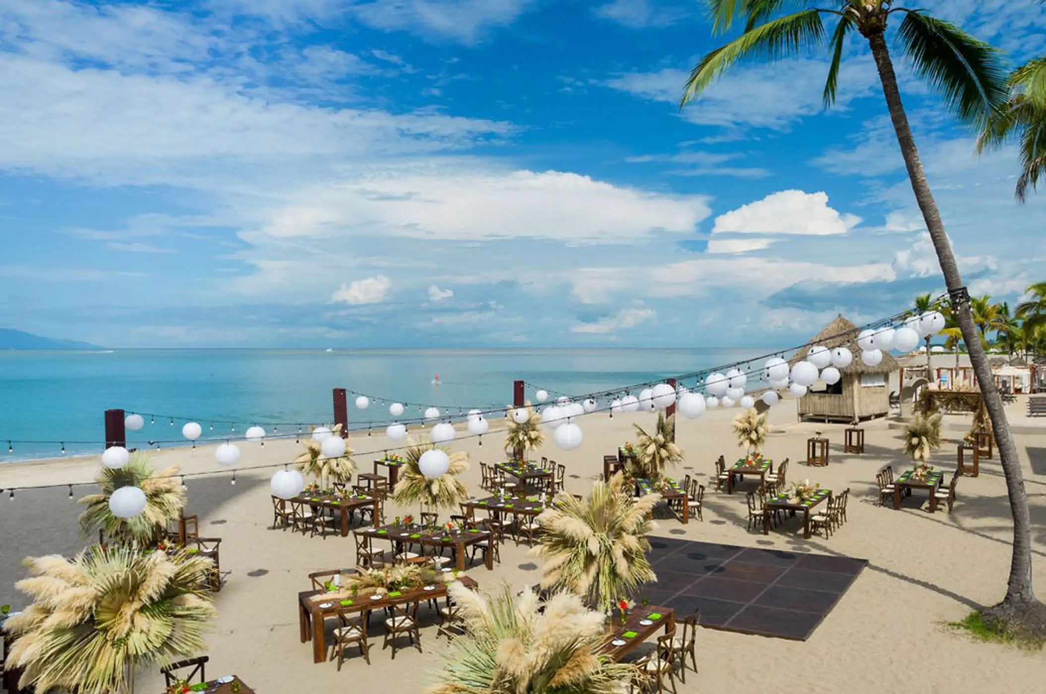Beach wedding reception setup with paper lanterns and pampas grass at Marriott Puerto Vallarta