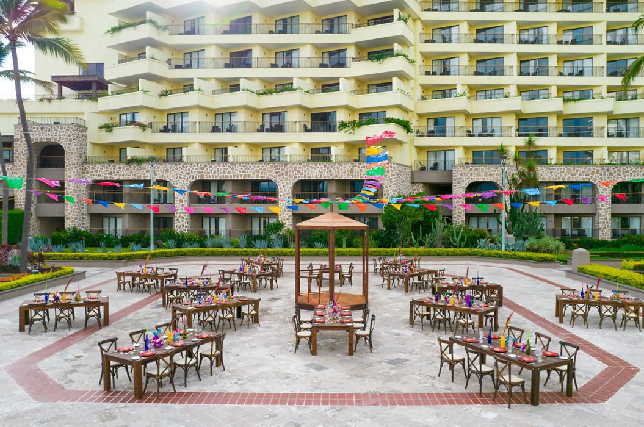 Outdoor wedding reception with colorful banners and wooden tables at Marriott Puerto Vallarta, Puerto Vallarta