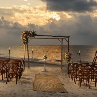 Beachfront wedding ceremony setup with wooden chairs and arch at Melia Cozumel, Cozumel