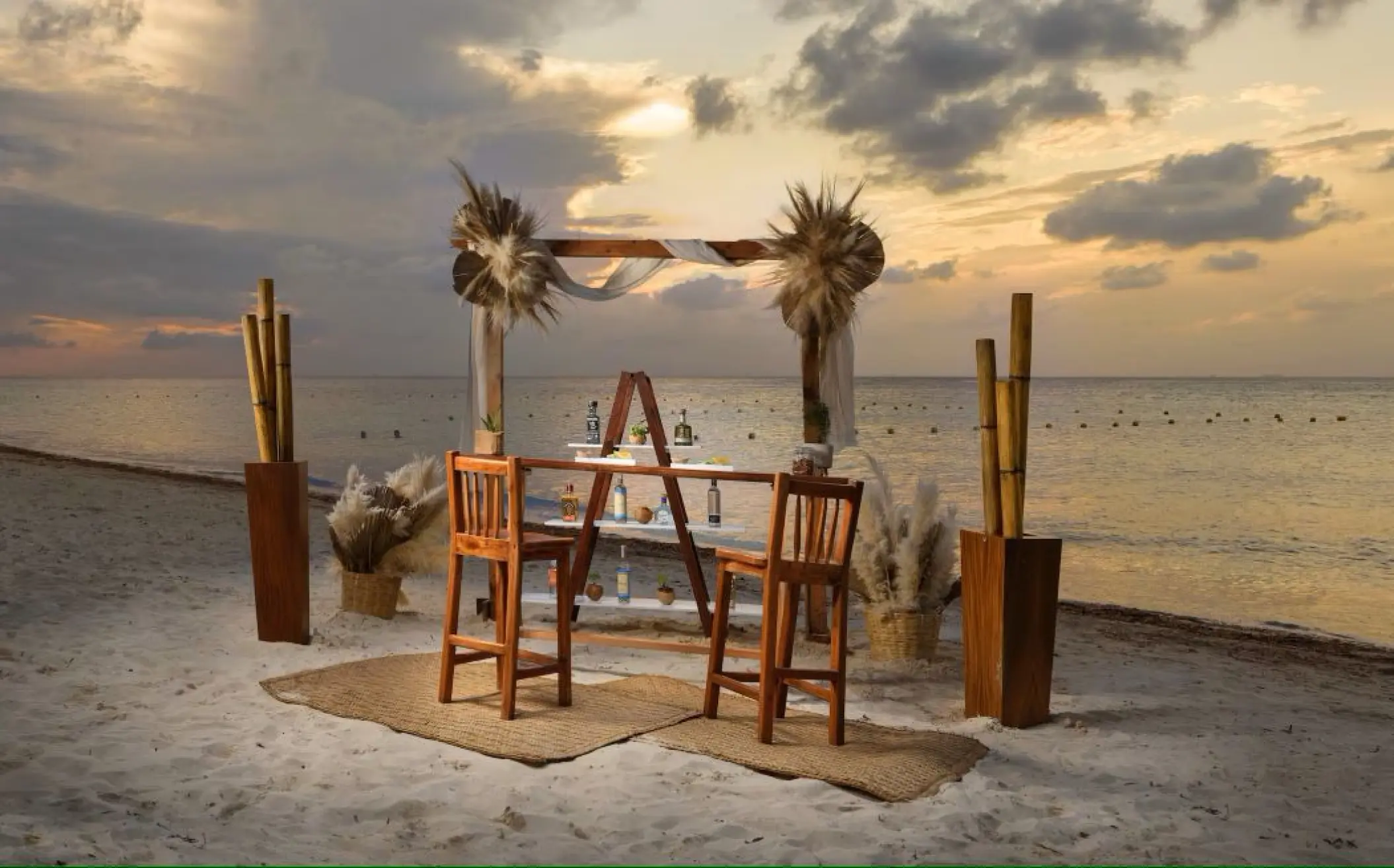 Beachfront wedding reception setup with a wooden bar and pampas grass at Melia Cozumel, Cozumel