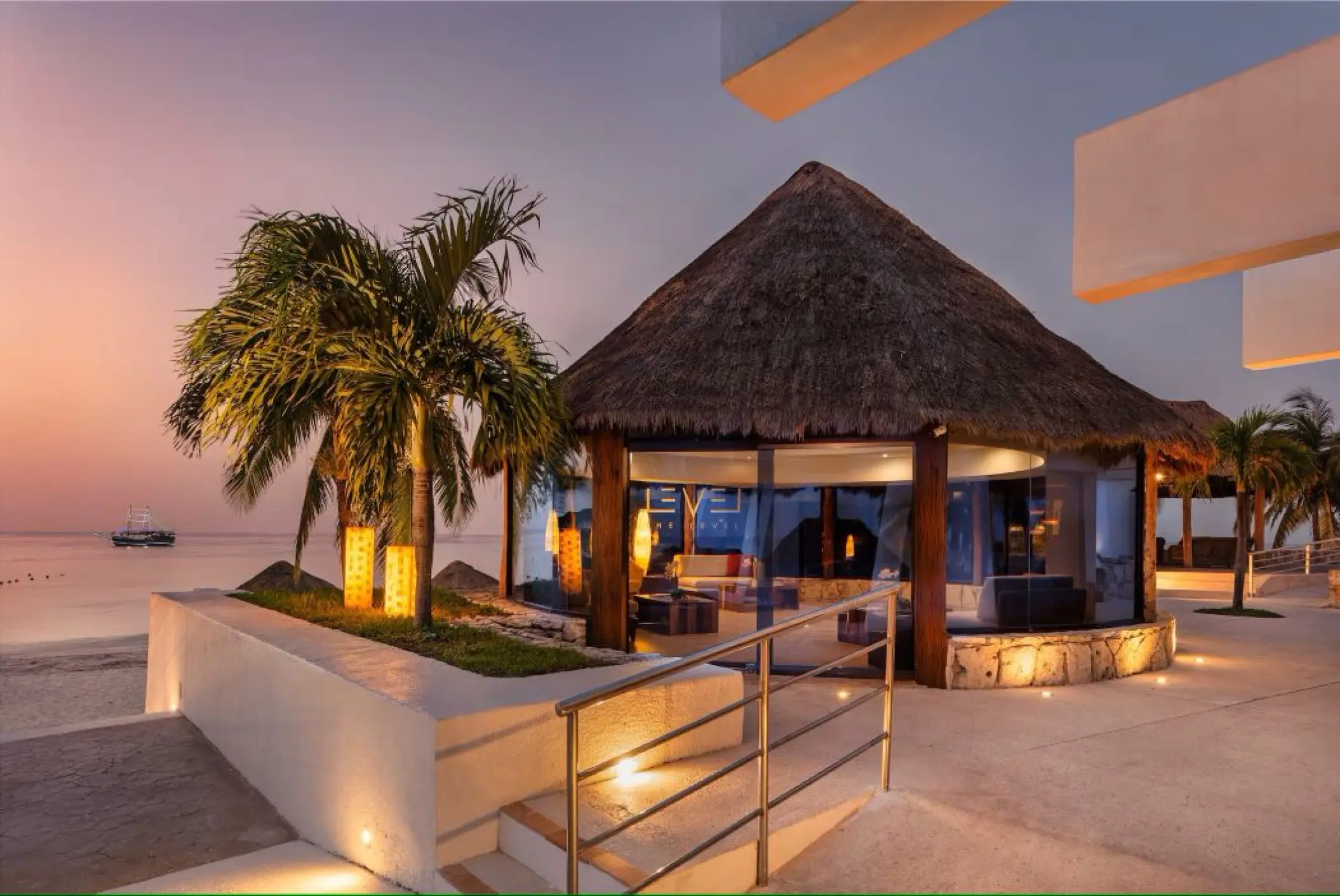 Thatched-roof pavilion and palm trees at Melia Cozumel during sunset, Cozumel
