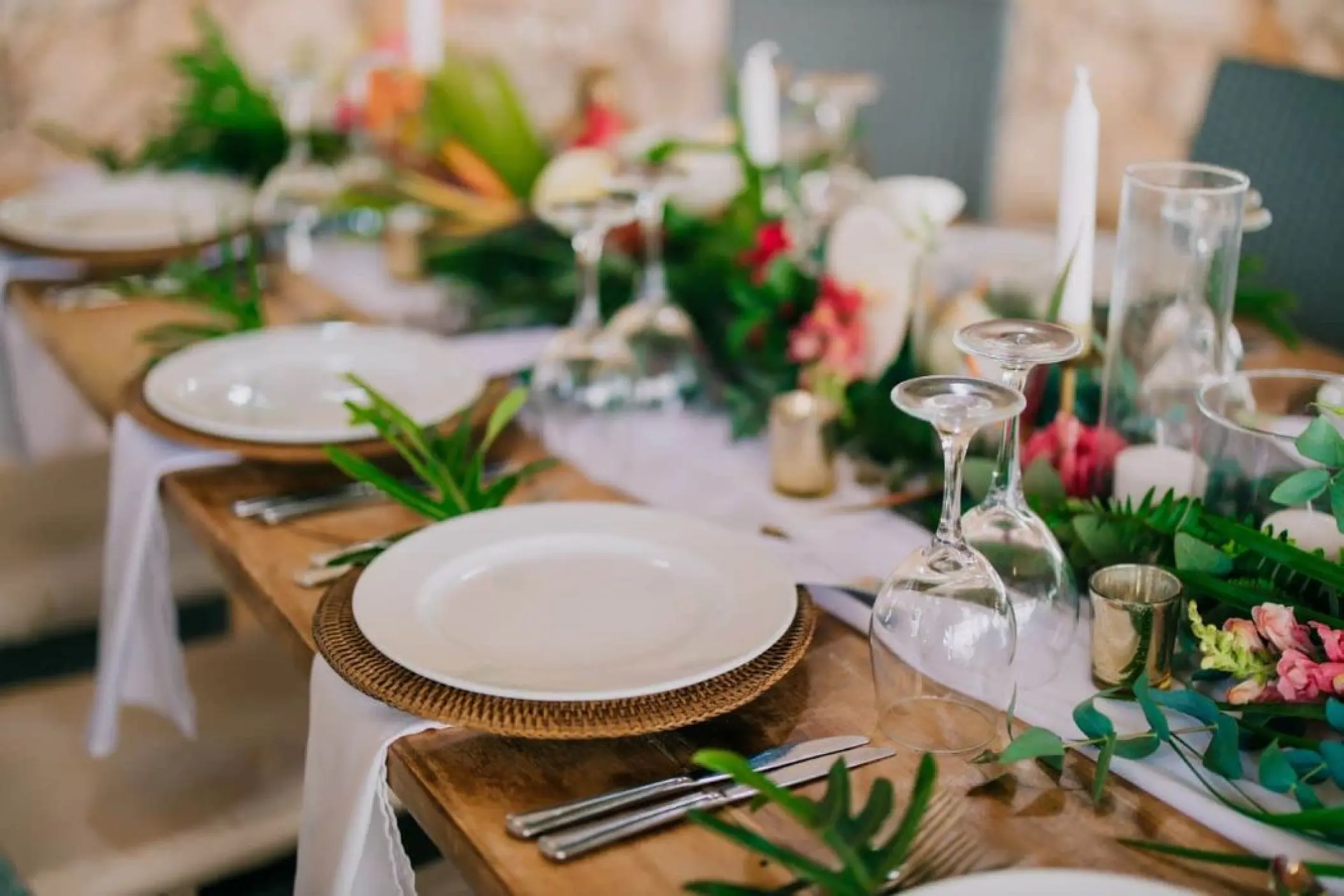 Tropical wedding reception table with floral runner and woven chargers at Melia Cozumel