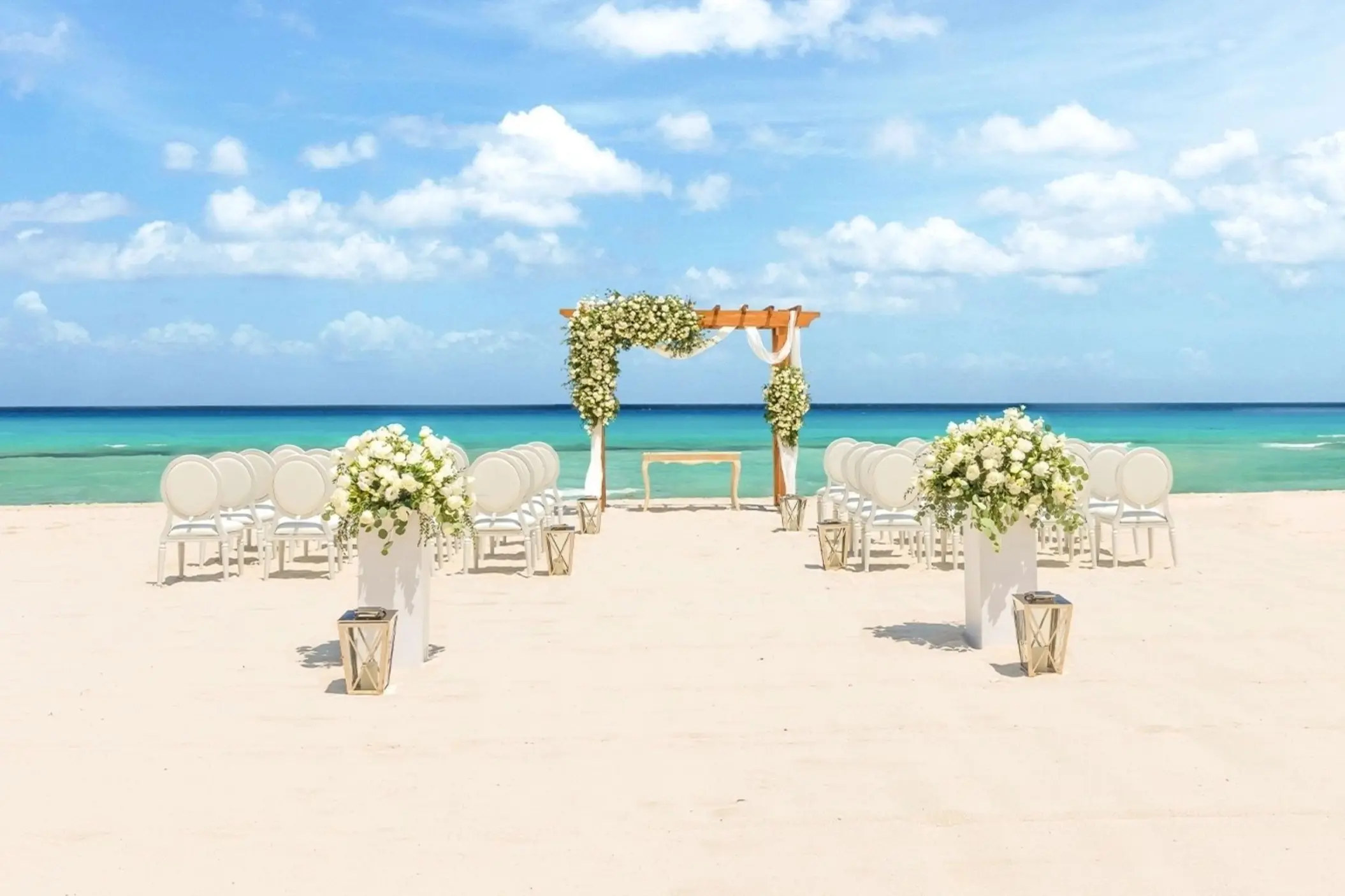 Beachfront wedding ceremony setup with white floral arch at Moon Palace Jamaica, Ocho Rios