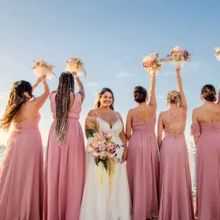 Bride and bridesmaids raising bouquets on a pier at Moon Palace Jamaica, Ocho Rios