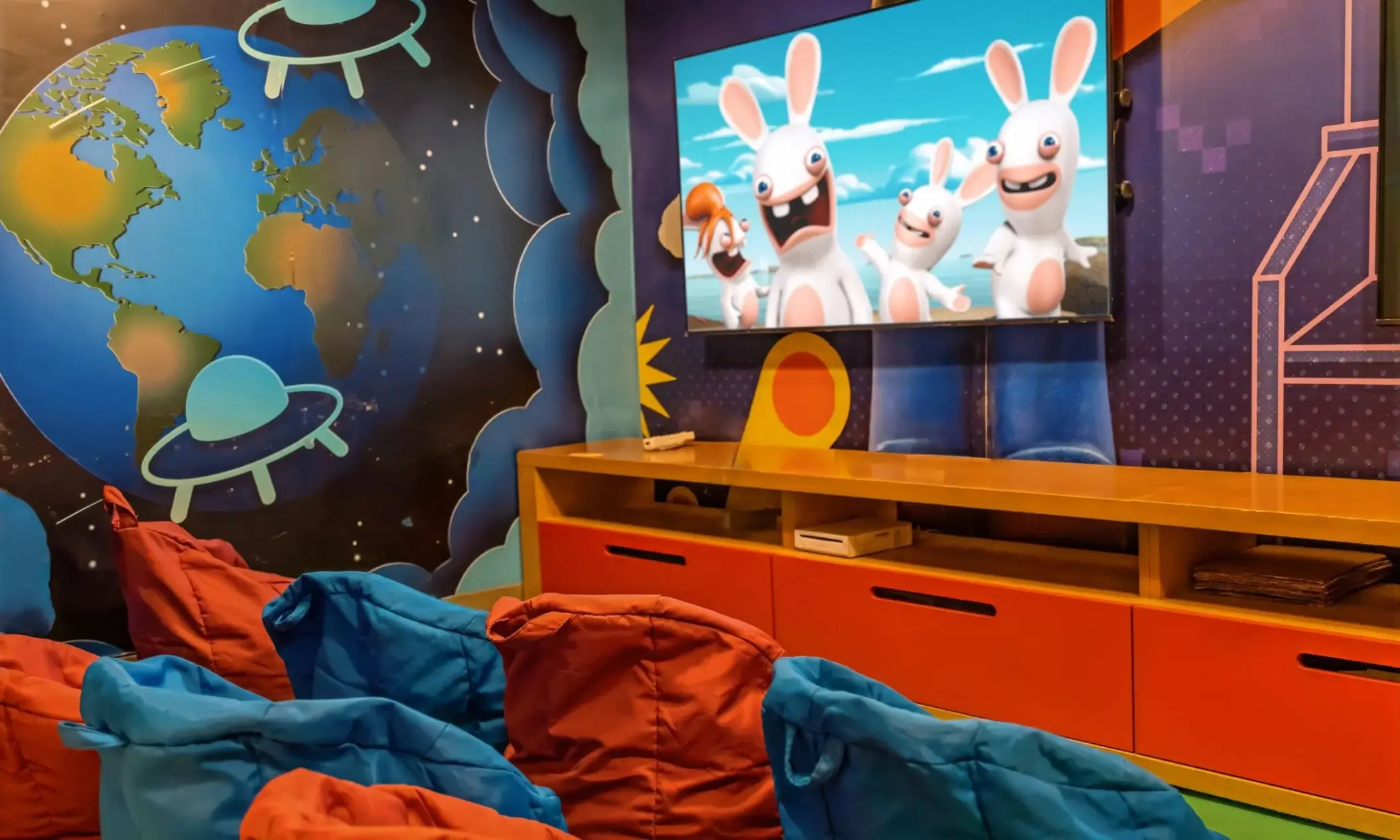 Colorful kids club movie room with bean bags and outer space wall mural at Moon Palace Jamaica, Ocho Rios