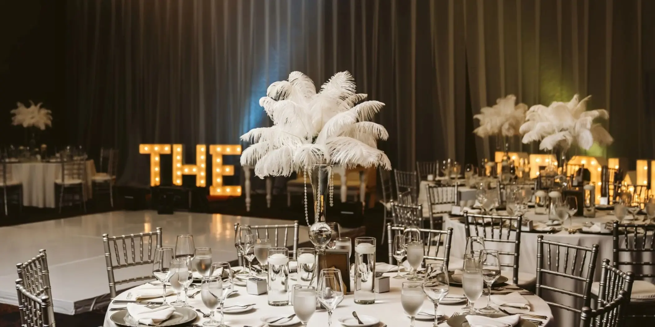 Ballroom wedding reception setup with feather centerpieces and light-up letters at Moon Palace Jamaica, Ocho Rios