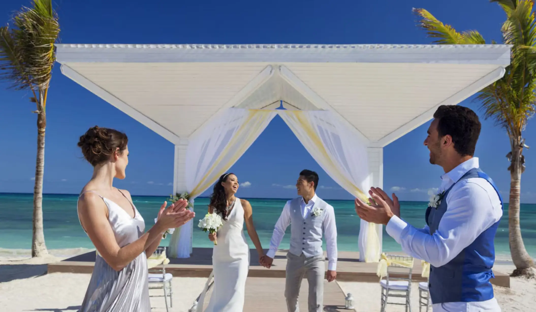 Bride and groom celebrated by guests under a beachfront gazebo at Mystique Holbox, Isla Holbox