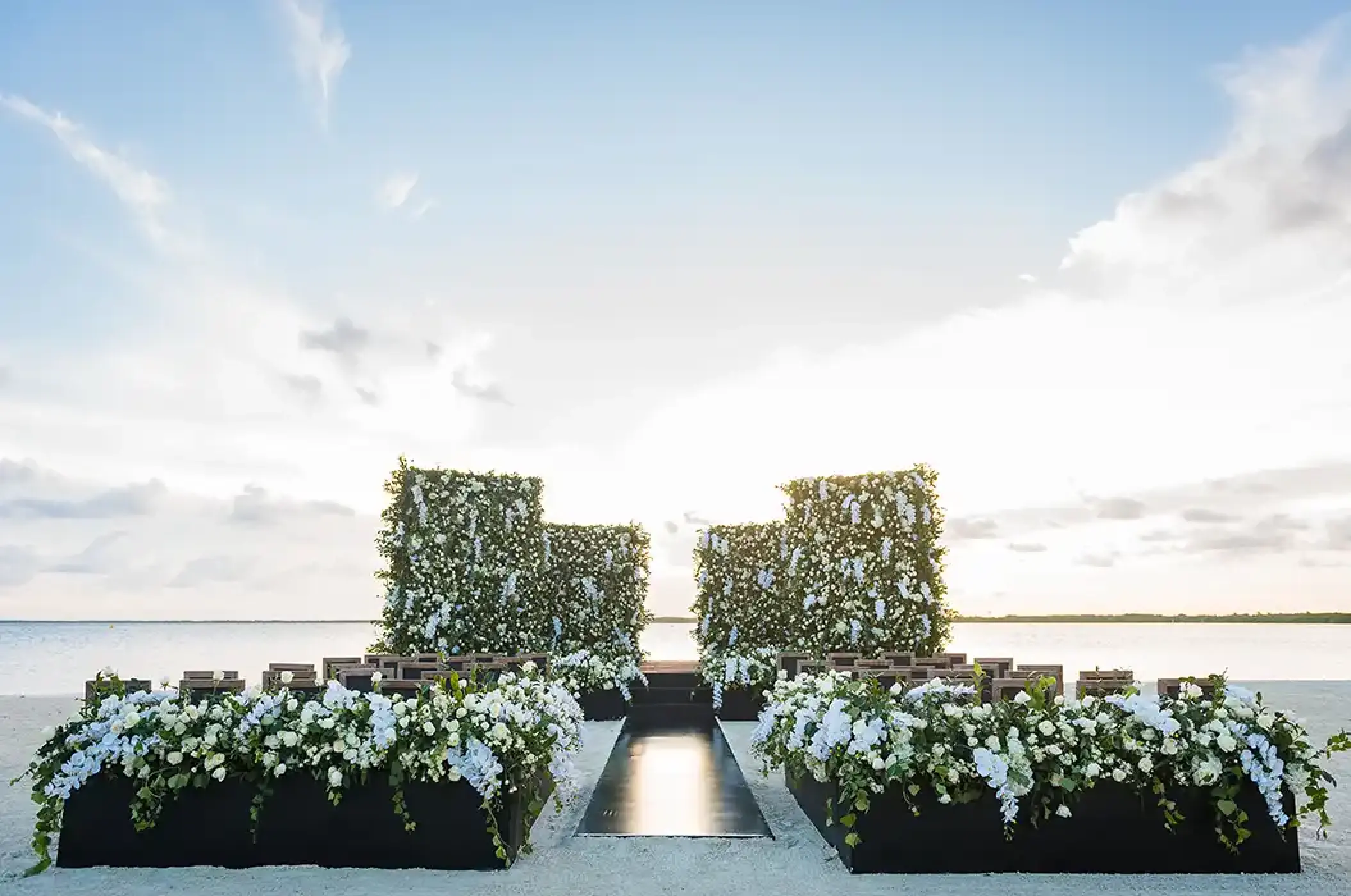 Beachfront wedding ceremony with white floral walls and aisle at Nizuc Resort, Cancun