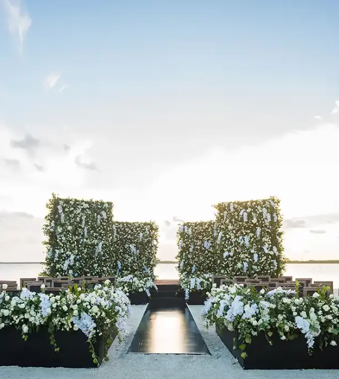 Beachfront wedding ceremony with white floral walls and aisle at Nizuc Resort, Cancun