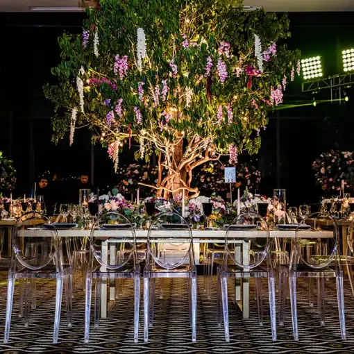 Indoor wedding reception at Nizuc Resort, Cancun featuring a large floral tree centerpiece and clear ghost chairs