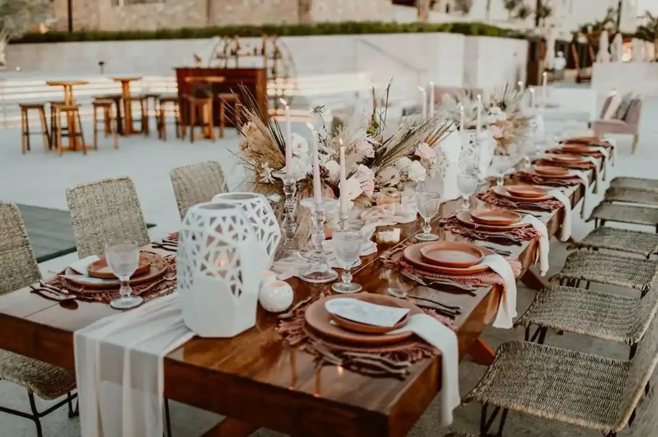 Long wooden wedding reception table with boho floral centerpieces at Nobu Hotel Los Cabos, Cabo San Lucas