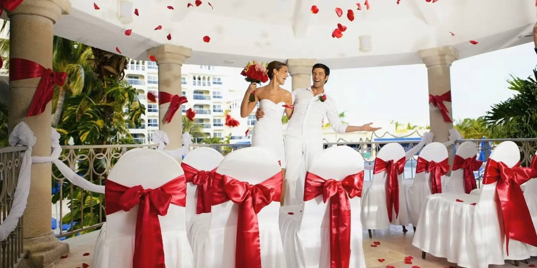Bride and groom under a gazebo with falling rose petals at Occidental Costa Cancun