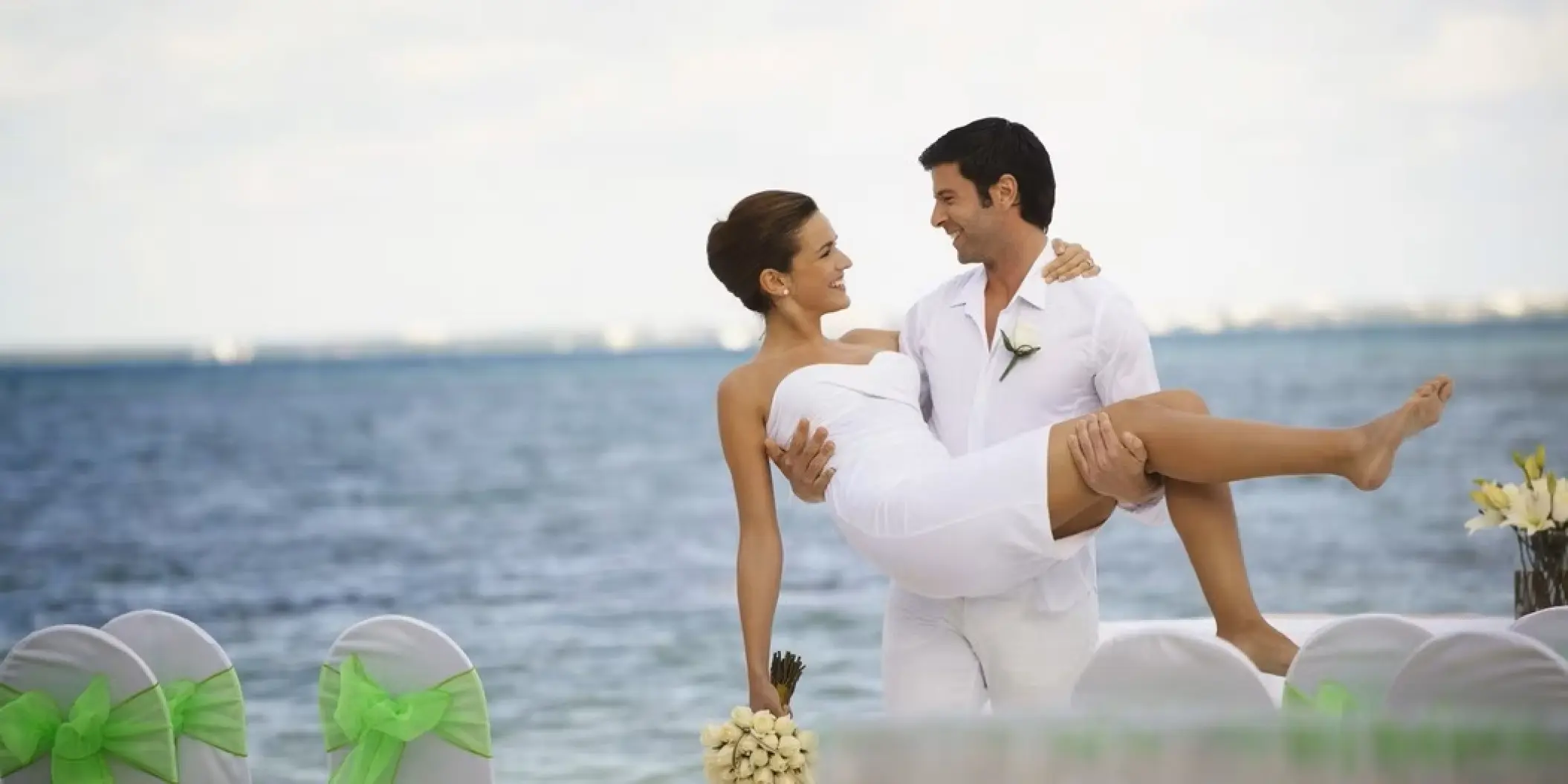 Groom carrying the bride on the beach at Occidental Costa Cancun