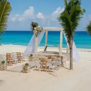 Beachfront wedding ceremony with a white gazebo and wooden chairs at Occidental Costa Cancun, Cancun