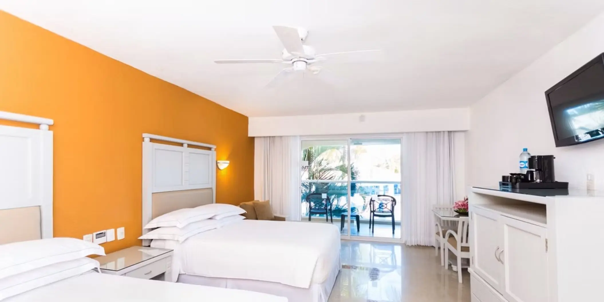 Double guest room with orange accent wall and balcony at Occidental Costa Cancun