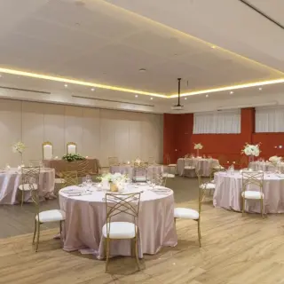 Indoor wedding reception with round tables and gold chairs at Ocean Allure Costa Mujeres, Cancun