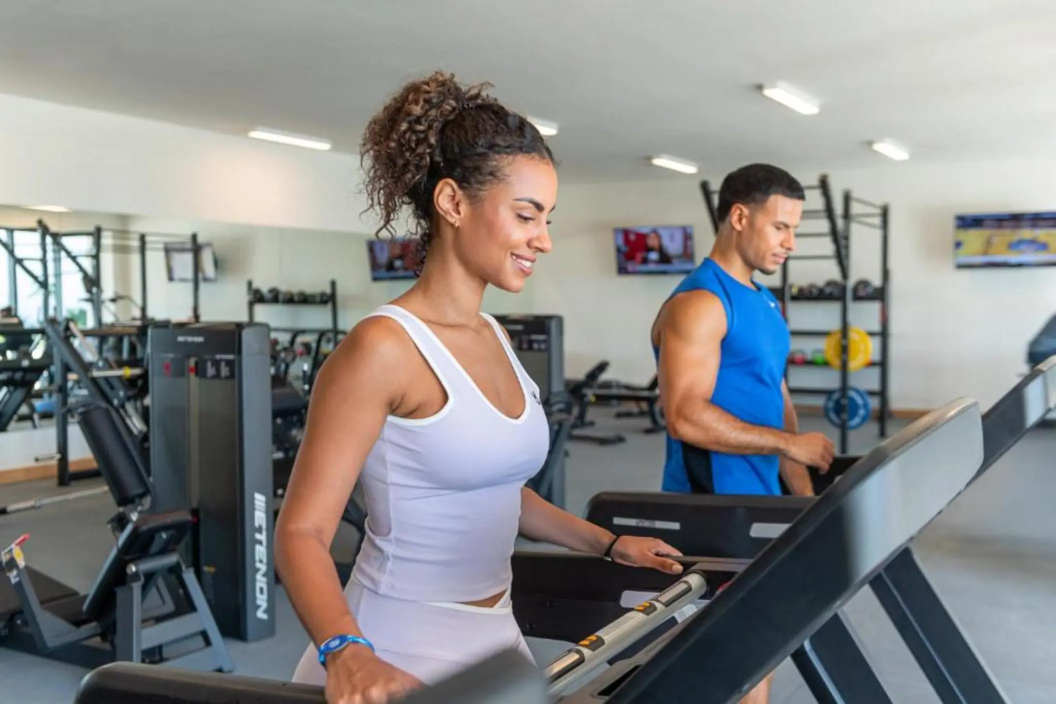 A man and woman using treadmills in the fitness center at Ocean Allure Costa Mujeres, Cancun