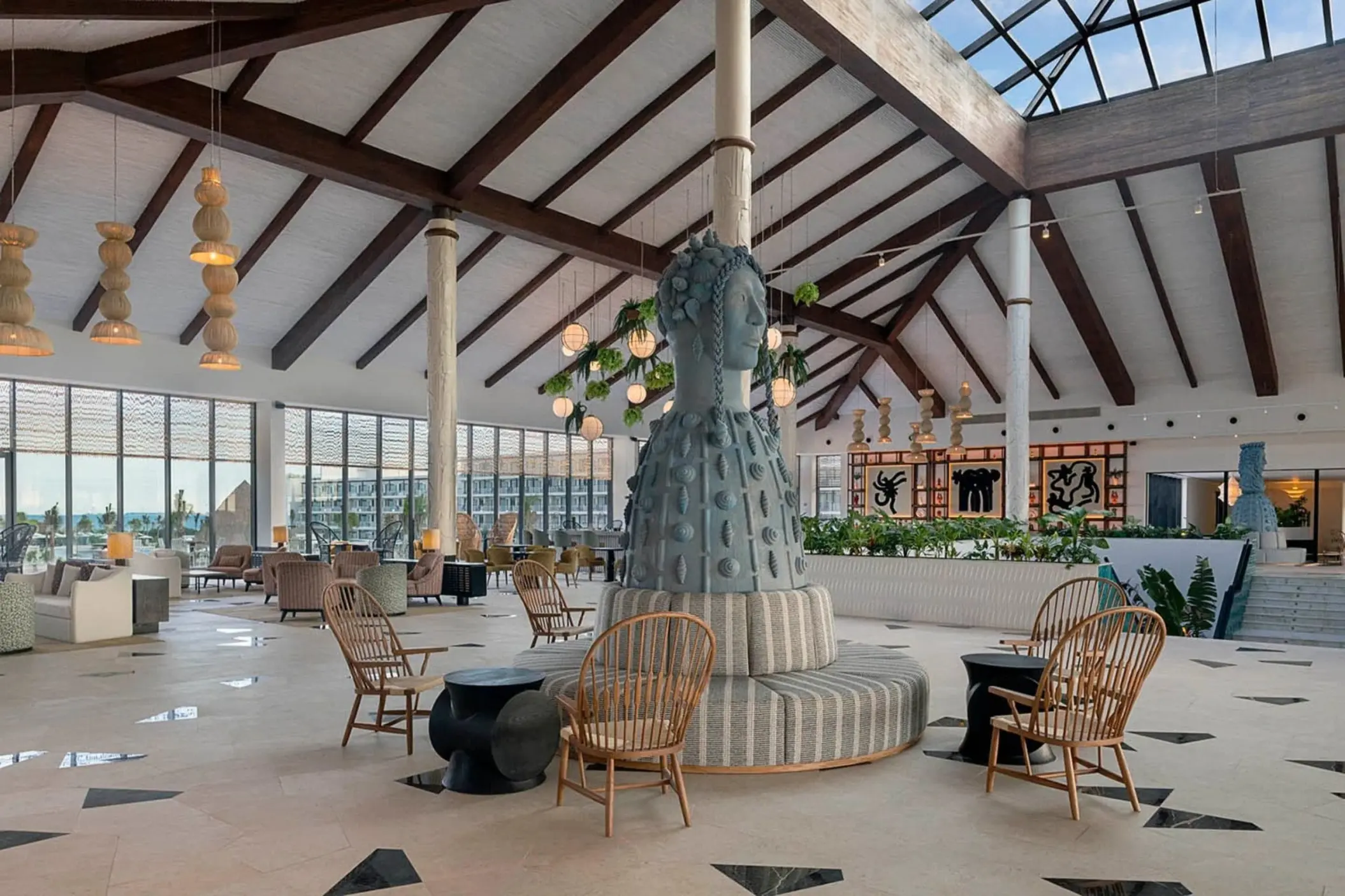 Modern open-air lobby with a large statue and wicker seating at Ocean Allure Costa Mujeres, Cancun