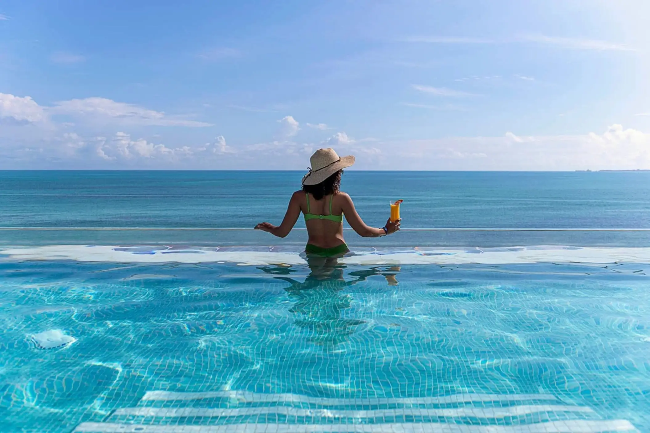 Woman holding a drink in the rooftop infinity pool at Ocean Allure Costa Mujeres, Cancun