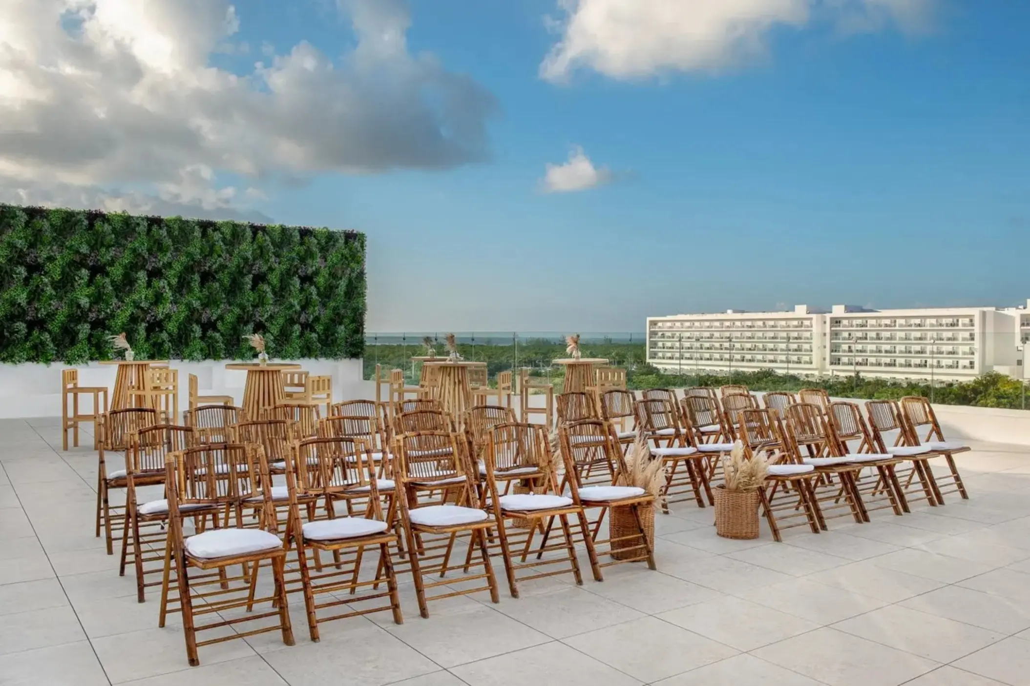 Rooftop wedding ceremony setup with wooden chairs and greenery wall at Ocean Allure Costa Mujeres, Cancun