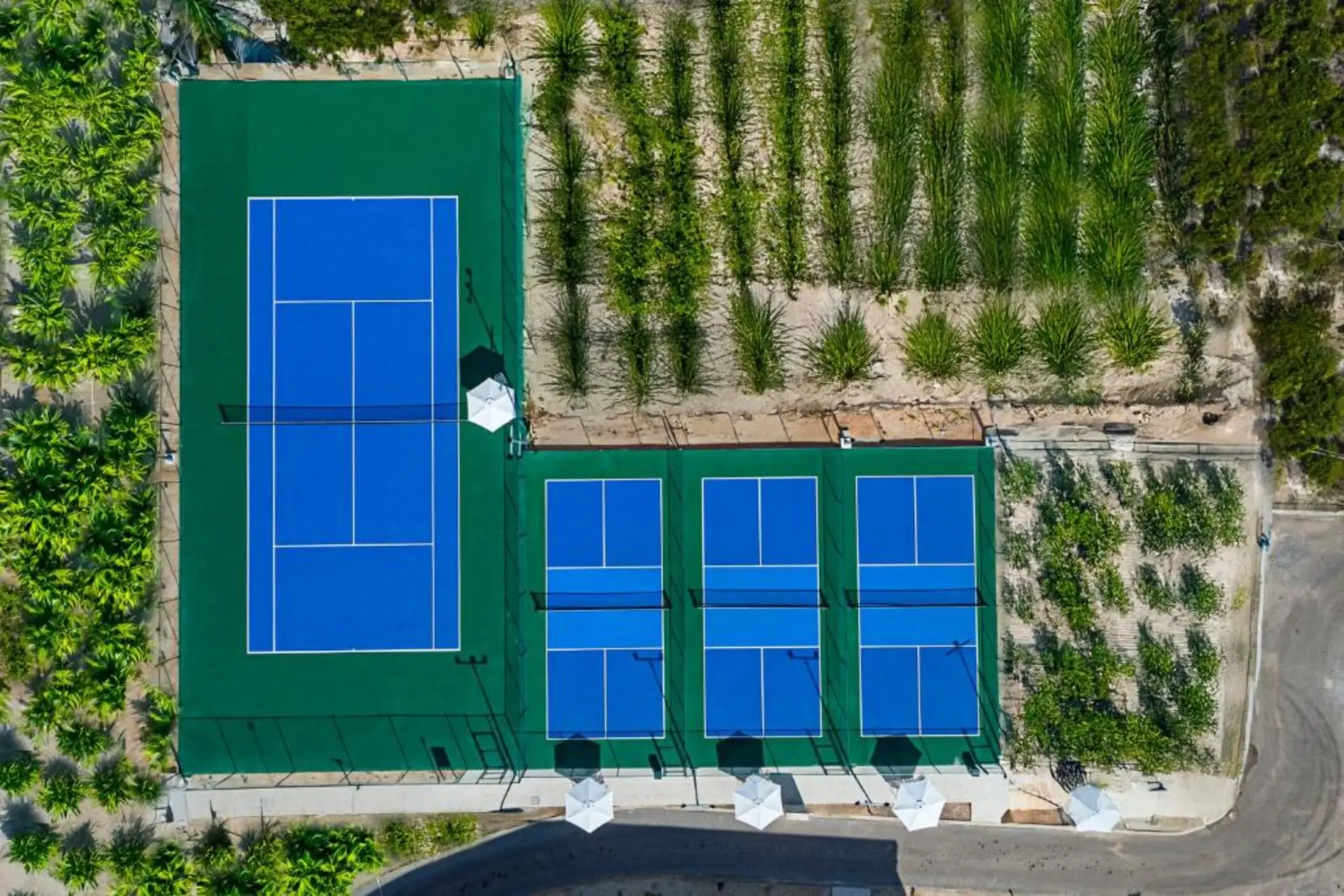 Aerial view of the blue tennis and pickleball courts at Ocean Allure Costa Mujeres, Cancun