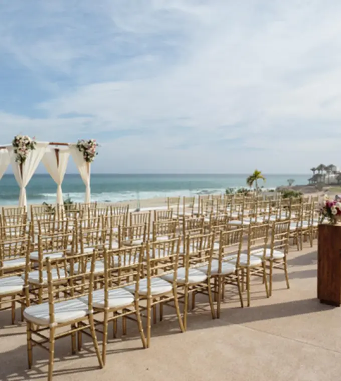 Ocean terrace wedding ceremony with gold chairs and white fabric arch at Paradisus Los Cabos, Cabo San Lucas
