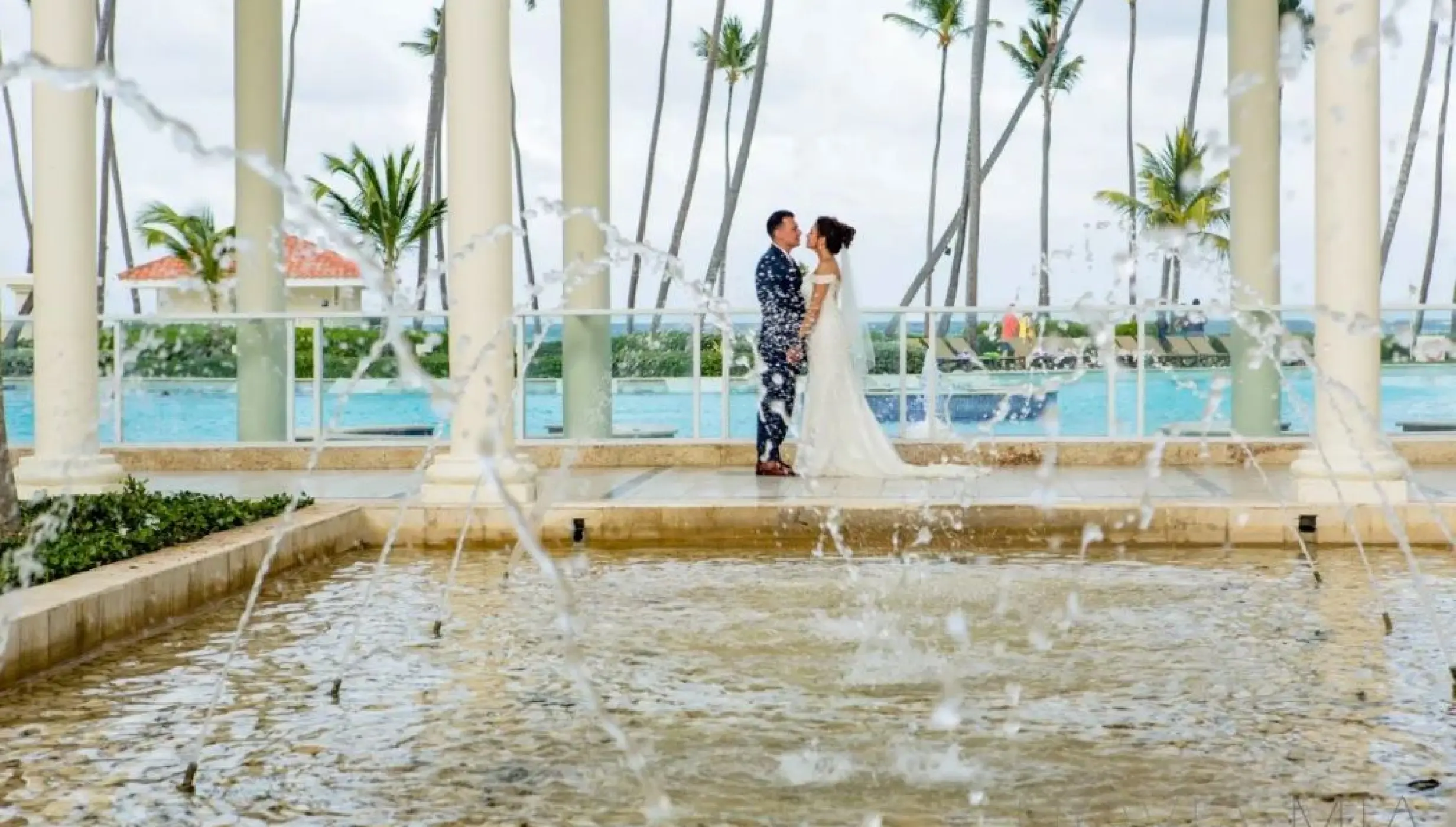 Bride and groom standing by a fountain at the Colonial Plaza venue at Paradisus Palma Real, Punta Cana