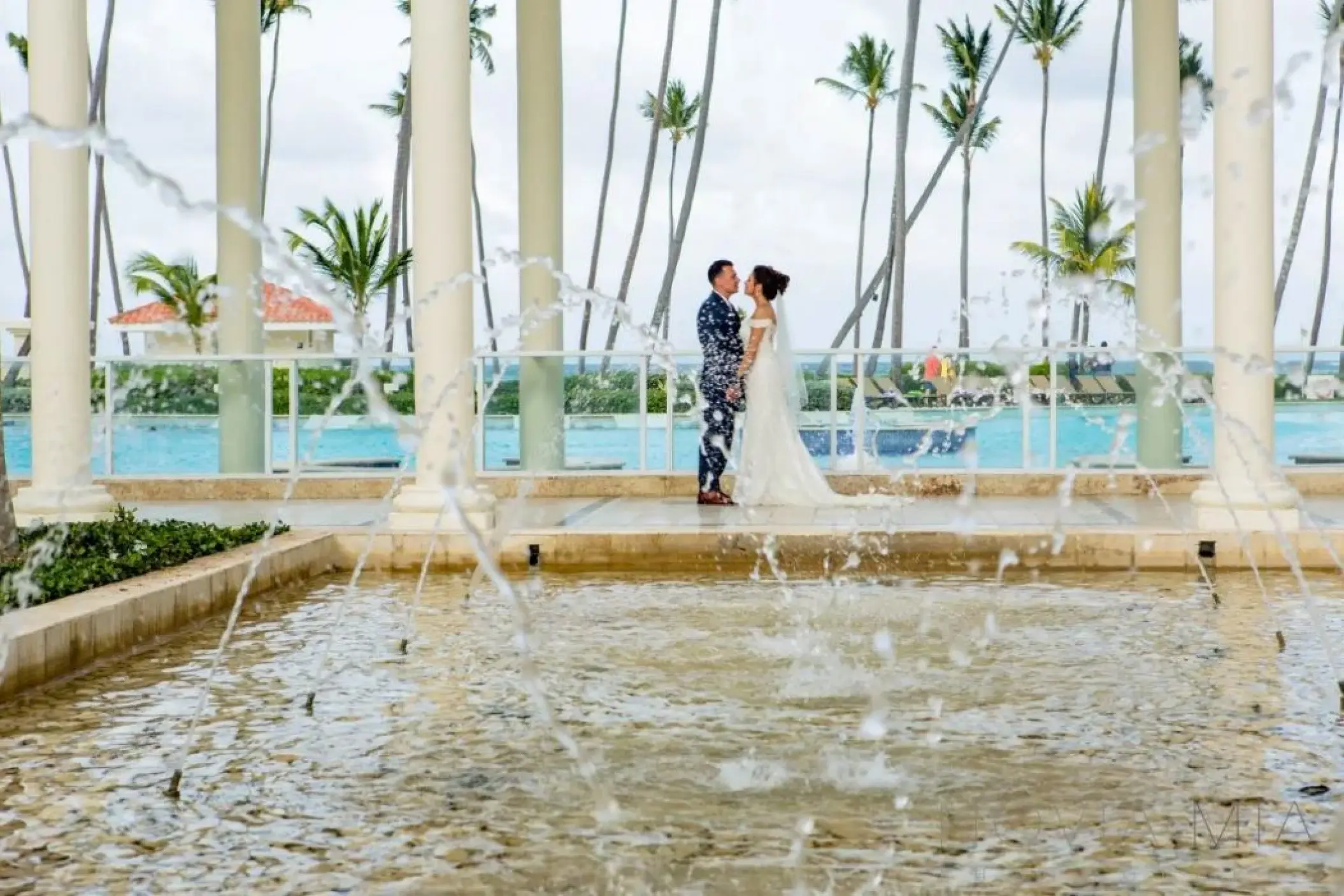 Bride and groom standing by a fountain at the Colonial Plaza venue at Paradisus Palma Real, Punta Cana