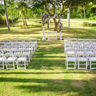 Garden wedding ceremony with white folding chairs and a floral arch at Paradisus Palma Real, Punta Cana