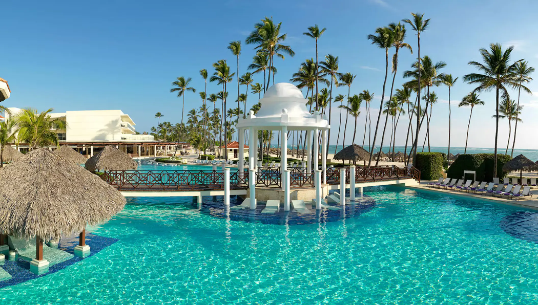 White domed gazebo and tropical swimming pool surrounded by palm trees at Paradisus Palma Real, Punta Cana
