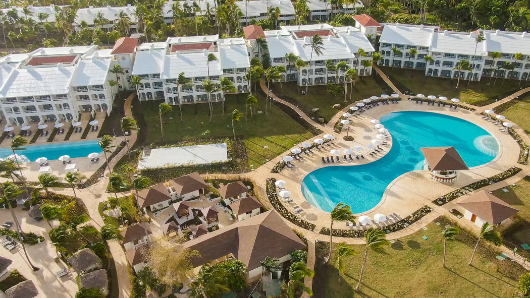Aerial view of swimming pools and white guest buildings at Paradisus Palma Real, Punta Cana