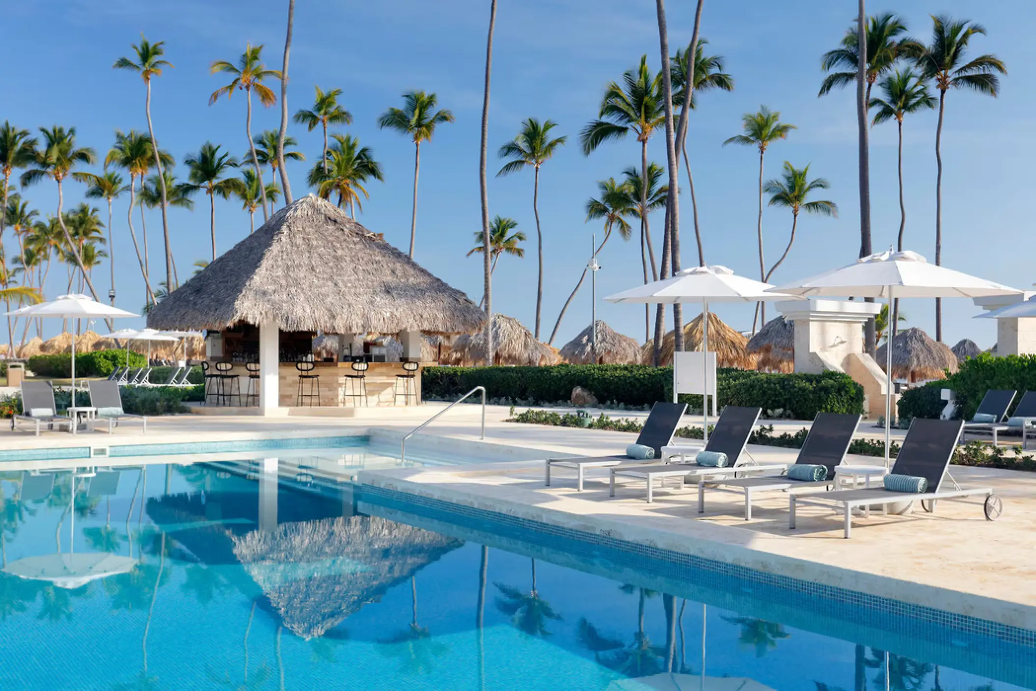 Swim-up pool bar and lounge chairs under palm trees at Paradisus Palma Real, Punta Cana