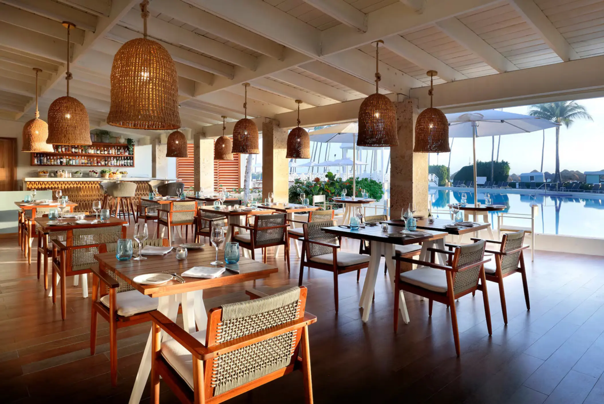 Open-air restaurant with woven pendant lights overlooking the pool at Paradisus Palma Real, Punta Cana
