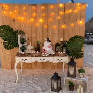 Rustic beach wedding cake table with string lights and tropical greenery at Paradisus Palma Real, Punta Cana