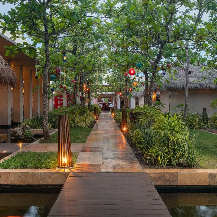 pathway lit by lanterns surrouded by lush greenery and resort buildings at Paradisus Playa Del Carmen