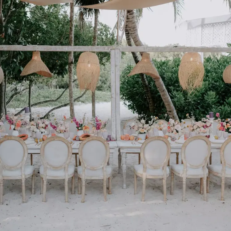 Wedding reception setup with hanging wicker lanterns and white chairs at Paradisus Playa Del Carmen