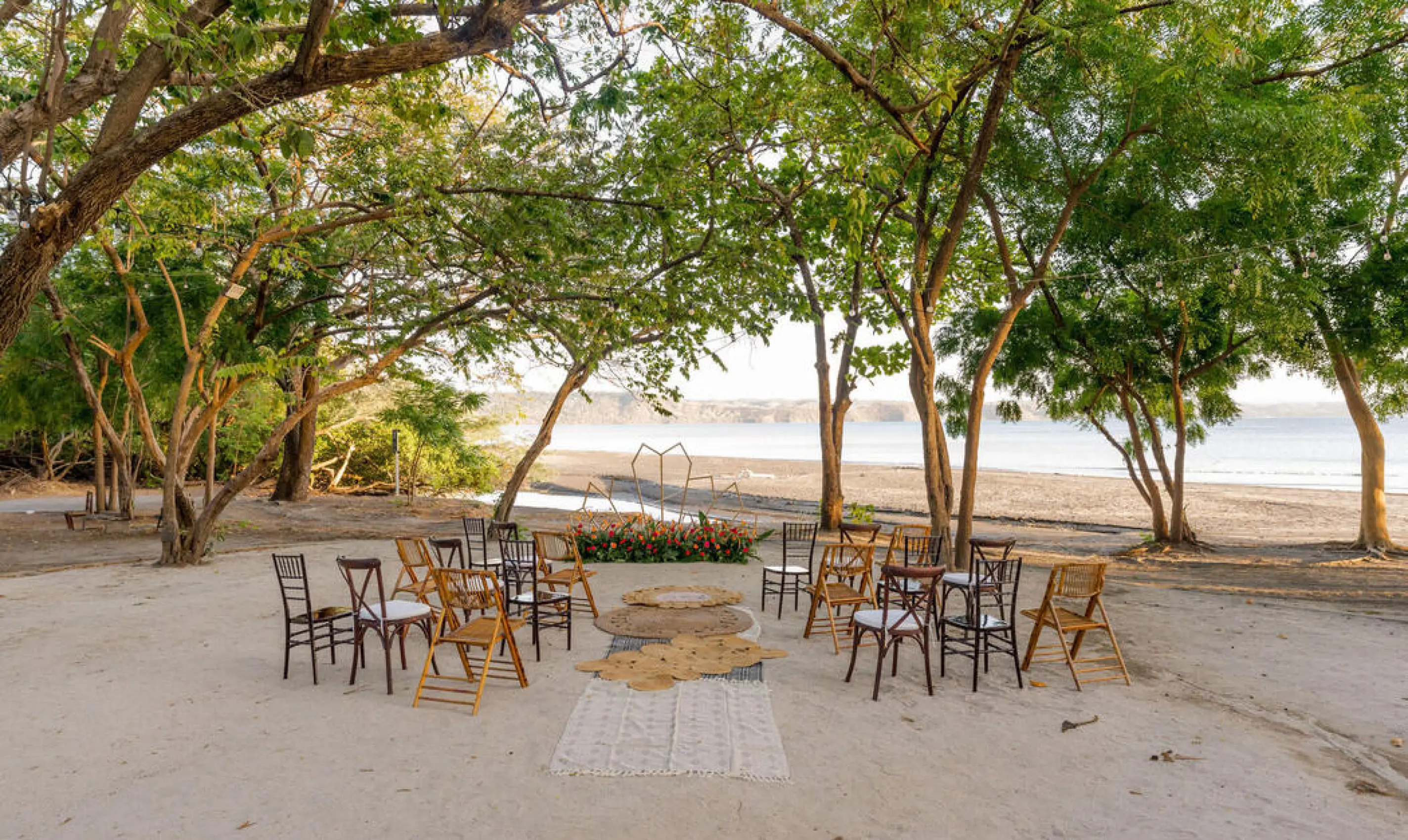 Beachfront wedding ceremony with wooden chairs under trees at Planet Hollywood Costa Rica, Papagayo