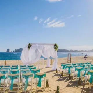 Beachfront wedding ceremony with turquoise sashes and white arch at Riu Palace Baja California, Cabo San Lucas